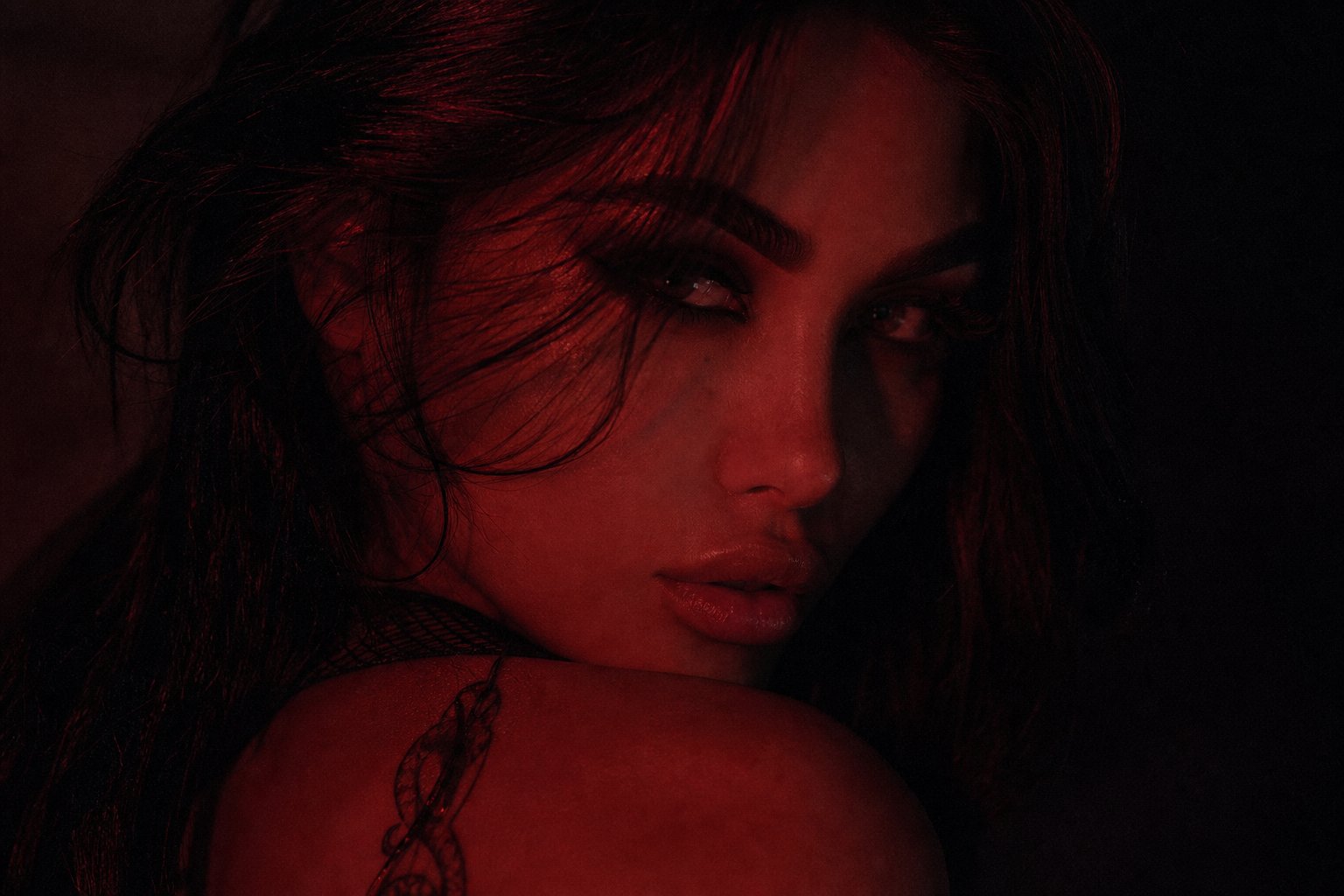 Retrato íntimo de una mujer en sombras rojas sobre negro