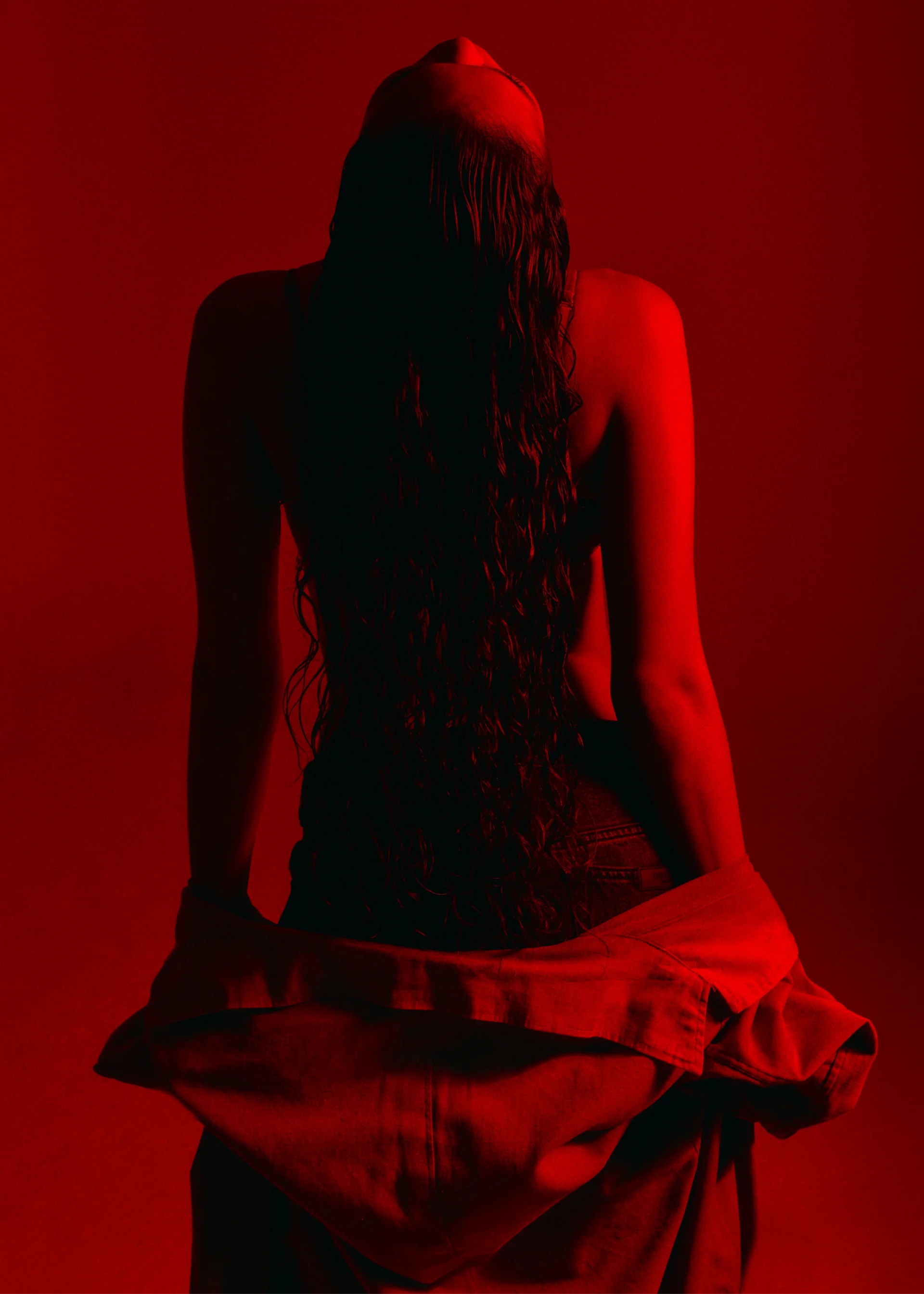 Figura de espaldas bajo luz roja de estudio